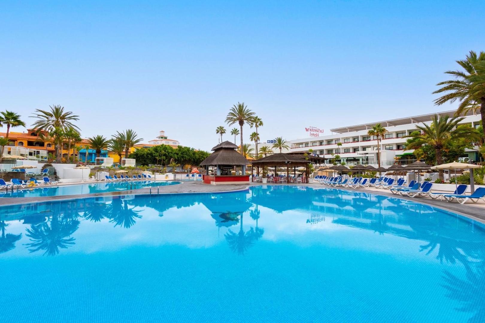 Alexandre Hotel La Siesta lielais āra baseins ar dzidru ūdeni, palmām un viesnīcas ēku fonā Playa de las Americas
