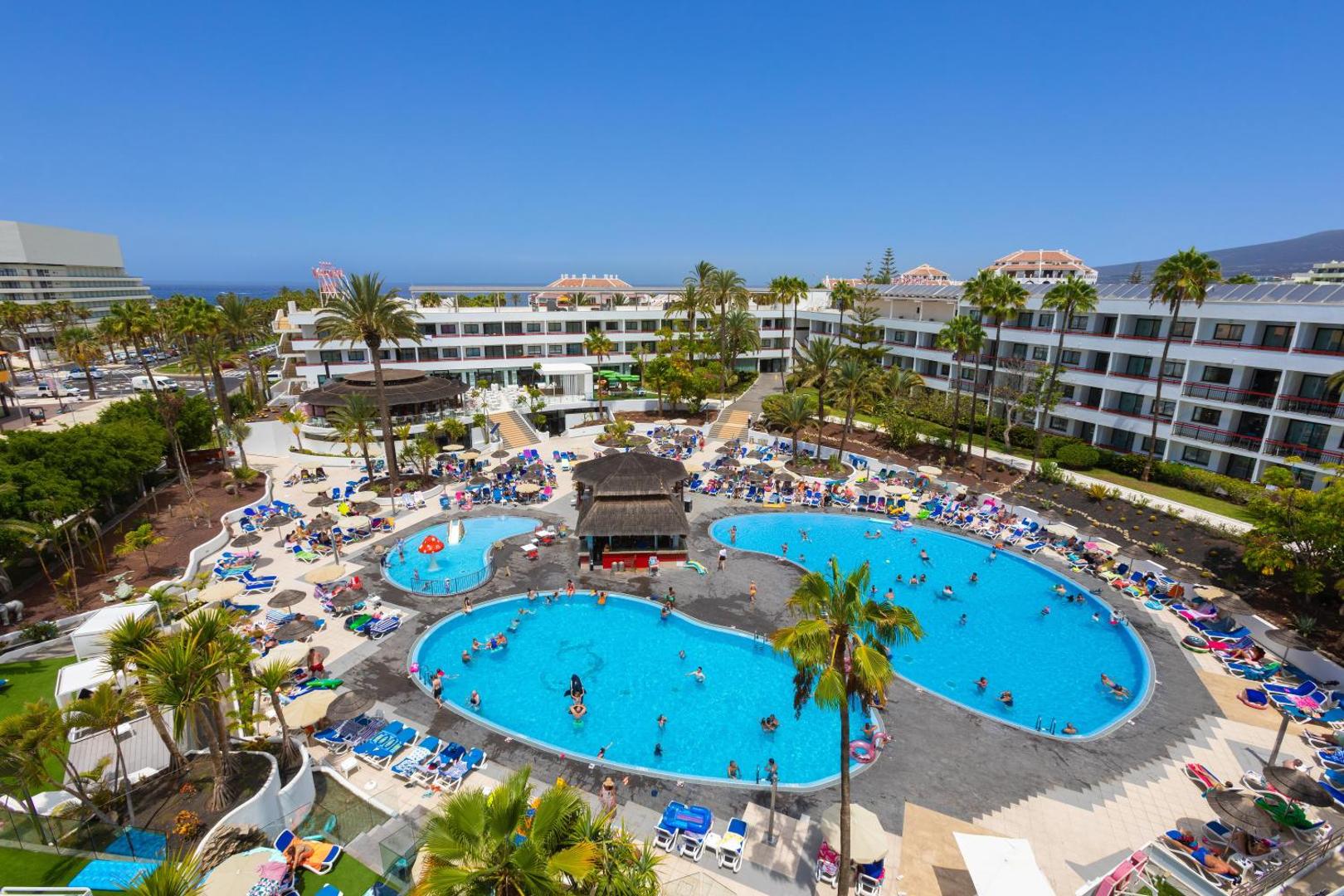 Alexandre Hotel La Siesta plašā teritorija ar vairākiem baseiniem, bāru un atpūtas zonām saulainā dienā Tenerifē