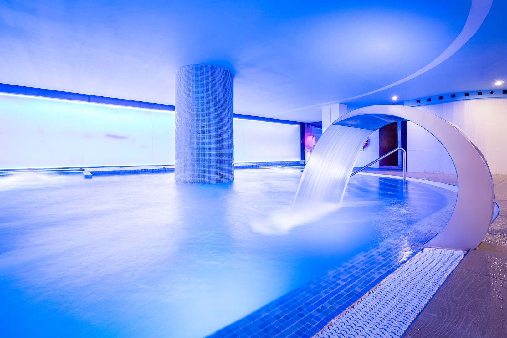 Alexandre Hotel La Siesta modernais spa baseins ar spēcīgu ūdens kaskādi un zilu neona apgaismojumu relaksējošai atpūtai Tenerifē