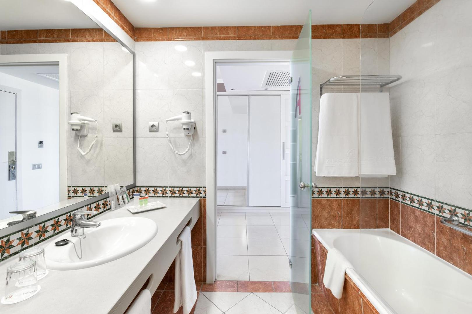Alexandre Hotel La Siesta viesnīcas numura vannas istaba ar vannu, lielu spoguli un gaišu flīžu apdari