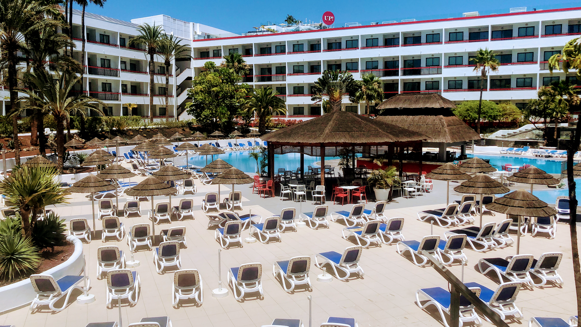 Alexandre Hotel La Siesta sauļošanās terase ar daudziem saulessargiem un zviļņiem pie viesnīcas korpusa un āra bāra