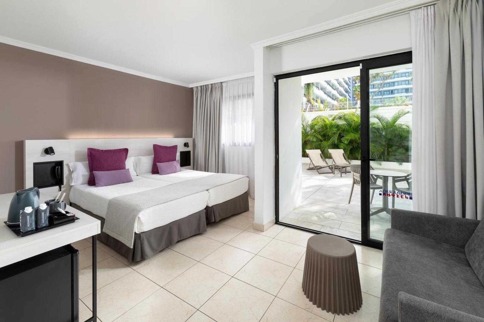Alexandre Hotel La Siesta moderns numurs ar divām gultām, dīvānu un izeju uz privātu terasi Playa de las Americas kūrortā