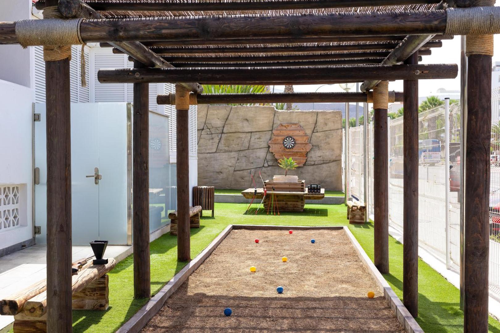 Alexandre Hotel La Siesta āra aktivitāšu zona ar bočes laukumu un mērķiem zem koka nojumes Tenerifes viesnīcas teritorijā.