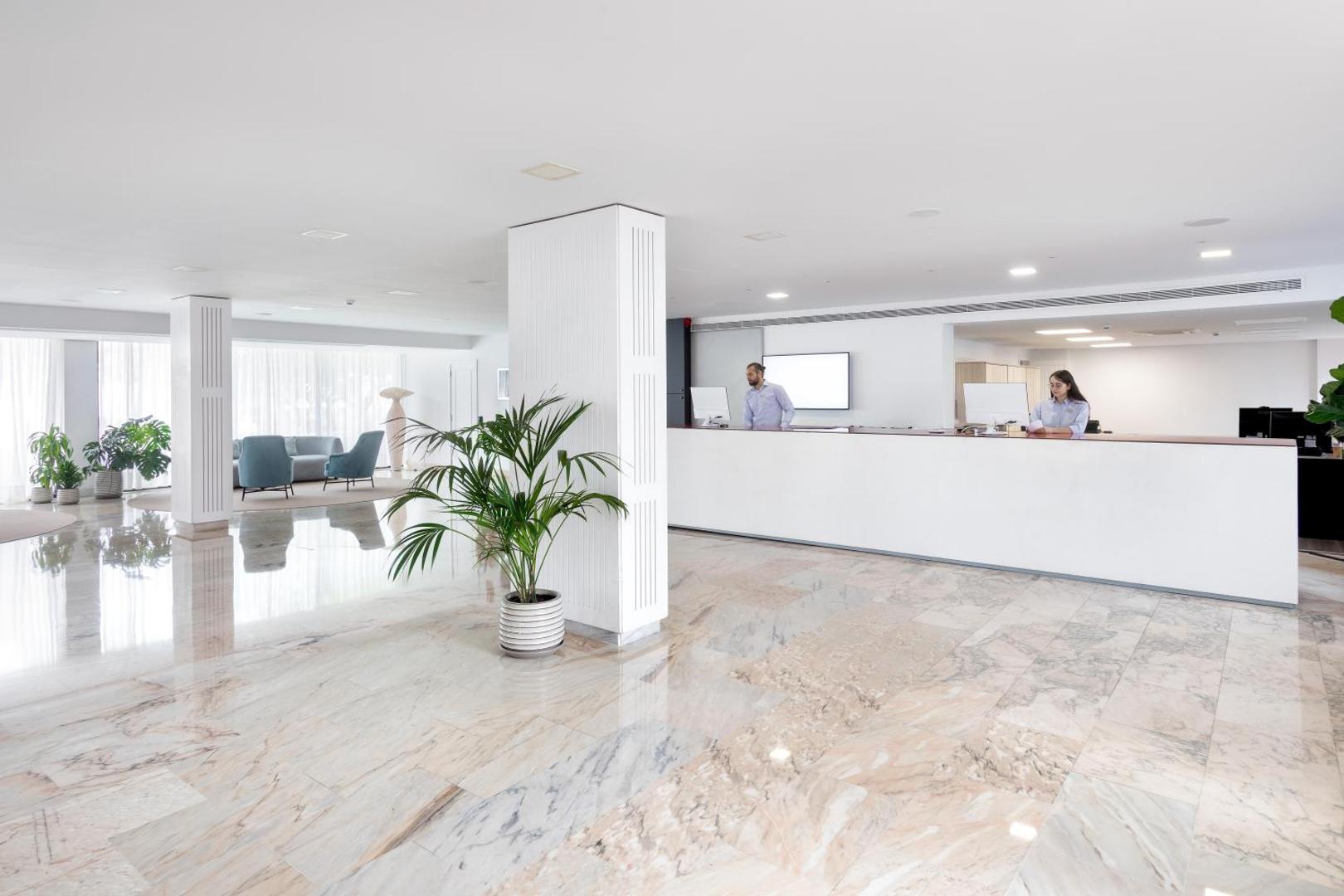 Alexandre Hotel La Siesta viesnīcas vestibils ar modernu recepcijas leti, marmora grīdu un gaišu interjeru Plajadelasamerikas kūrortā