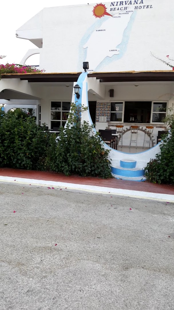 Nirvana Beach Hotel bāra zona ar augstajiem krēsliem un dekoratīvu Rodas salas karti uz sienas — ieeja viesnīcas kafejnīcā.