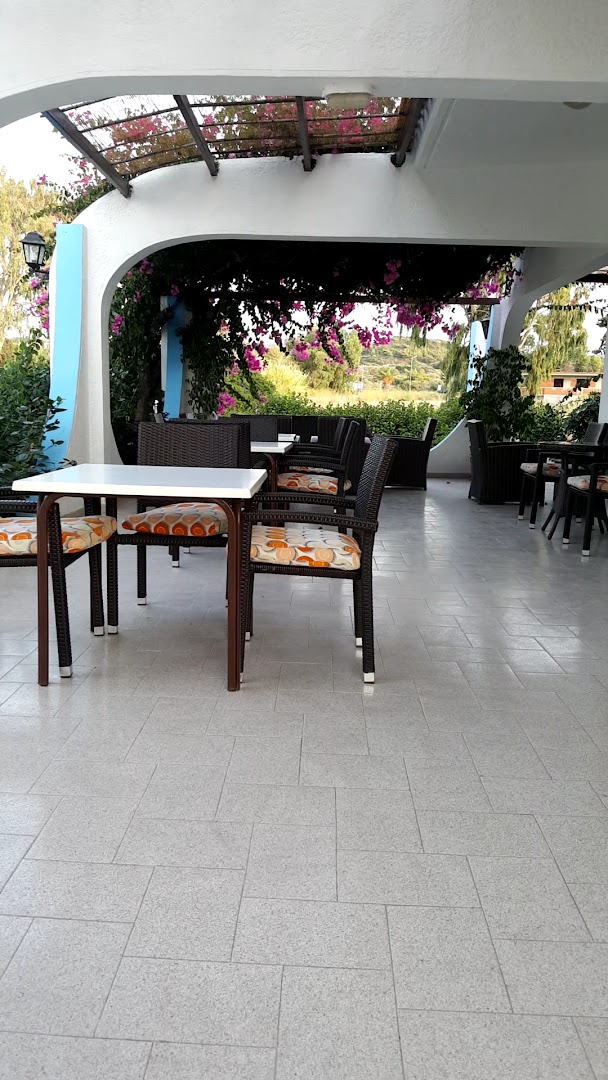 Nirvana Beach Hotel segtā āra terase ar pītiem krēsliem un ziedošām bugenvillijām dārza zonā