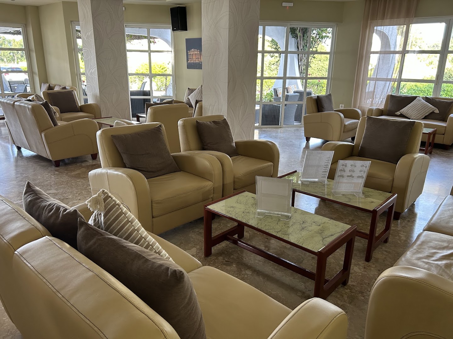 Nirvana Beach Hotel viesnīcas vestibils ar gaišiem ādas dīvāniem un atpūtas zonu — plaši logi un mājīga atmosfēra