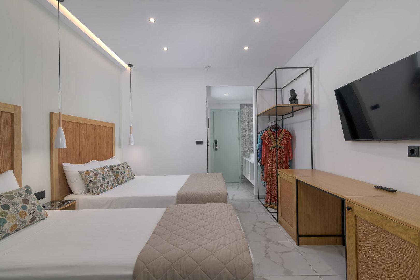 Nirvana Beach Hotel gaišs divvietīgs numurs ar modernām mēbelēm, TV, atvērtā tipa skapi un marmora flīžu grīdu.