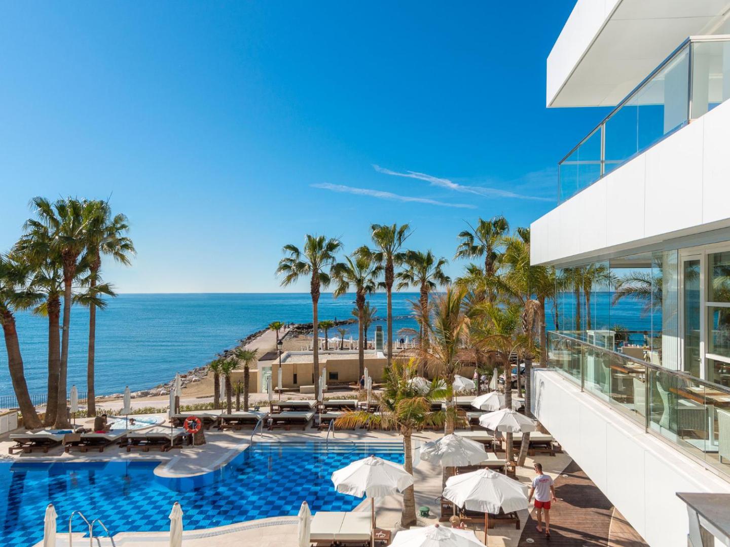 Viesnīcas Amare Beach Hotel Marbella terase un baseins ar skatu uz pludmali un zilo debess pamali