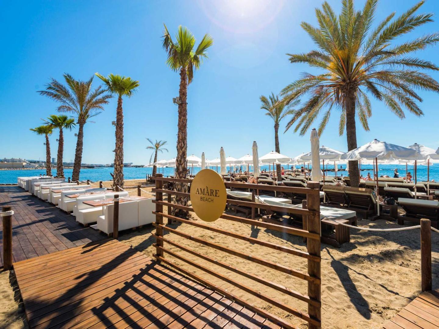 Amare Beach Hotel Marbella privātā pludmales zona ar saulessargiem, zviļņiem un palmām gaišā dienas laikā
