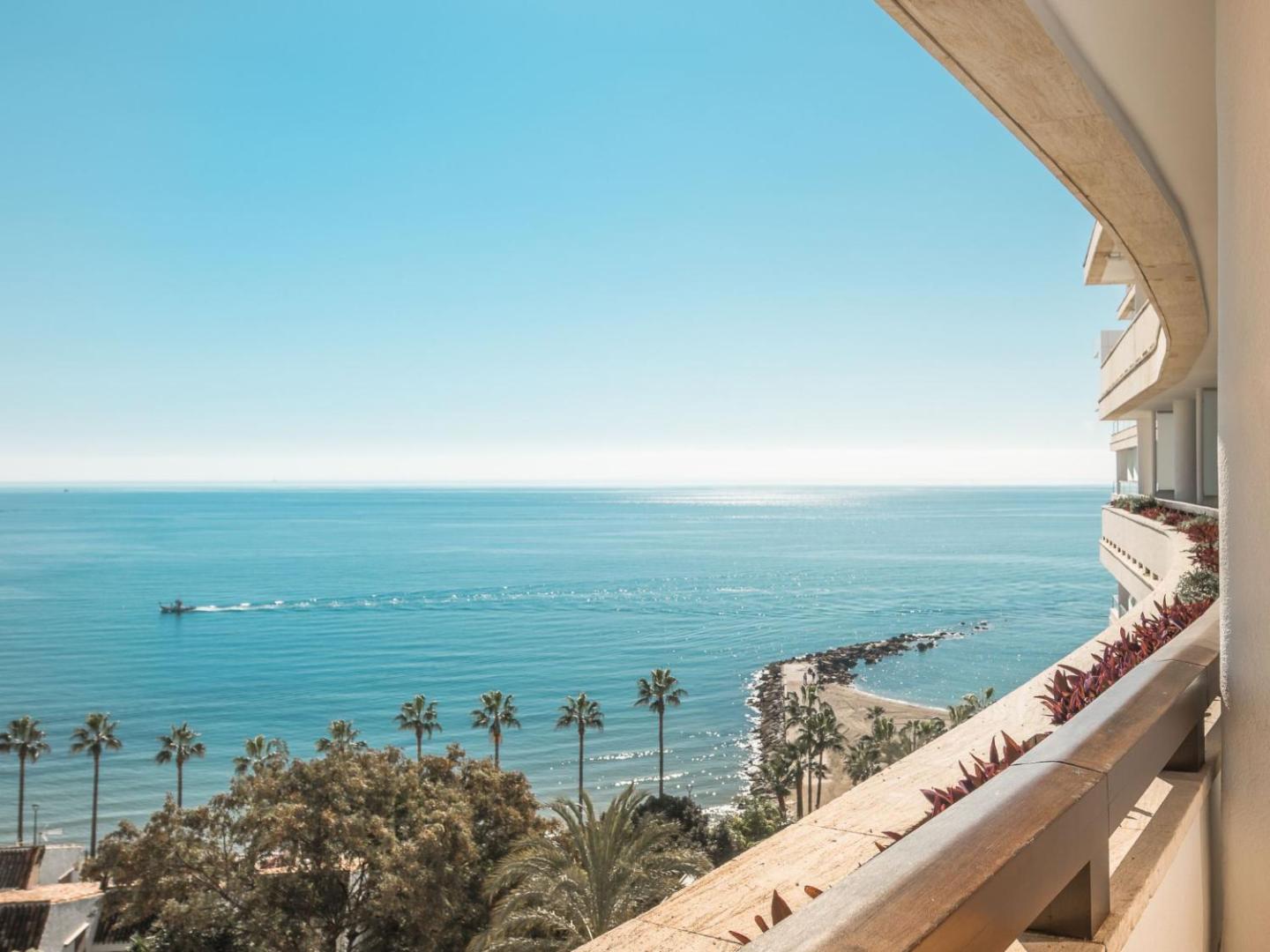 Skats no Amare Beach Hotel Marbella balkona uz Vidusjūru, palmām un piekrastes līniju saulainā dienā Spānijā