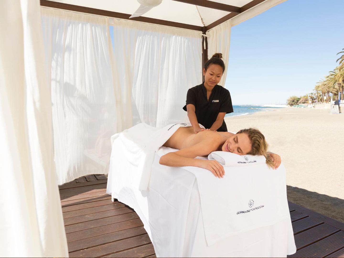 Masāžas procedūra brīvā dabā Amare Beach Hotel Marbella pludmales zonā zem baltas nojumes Marbeljas piekrastē