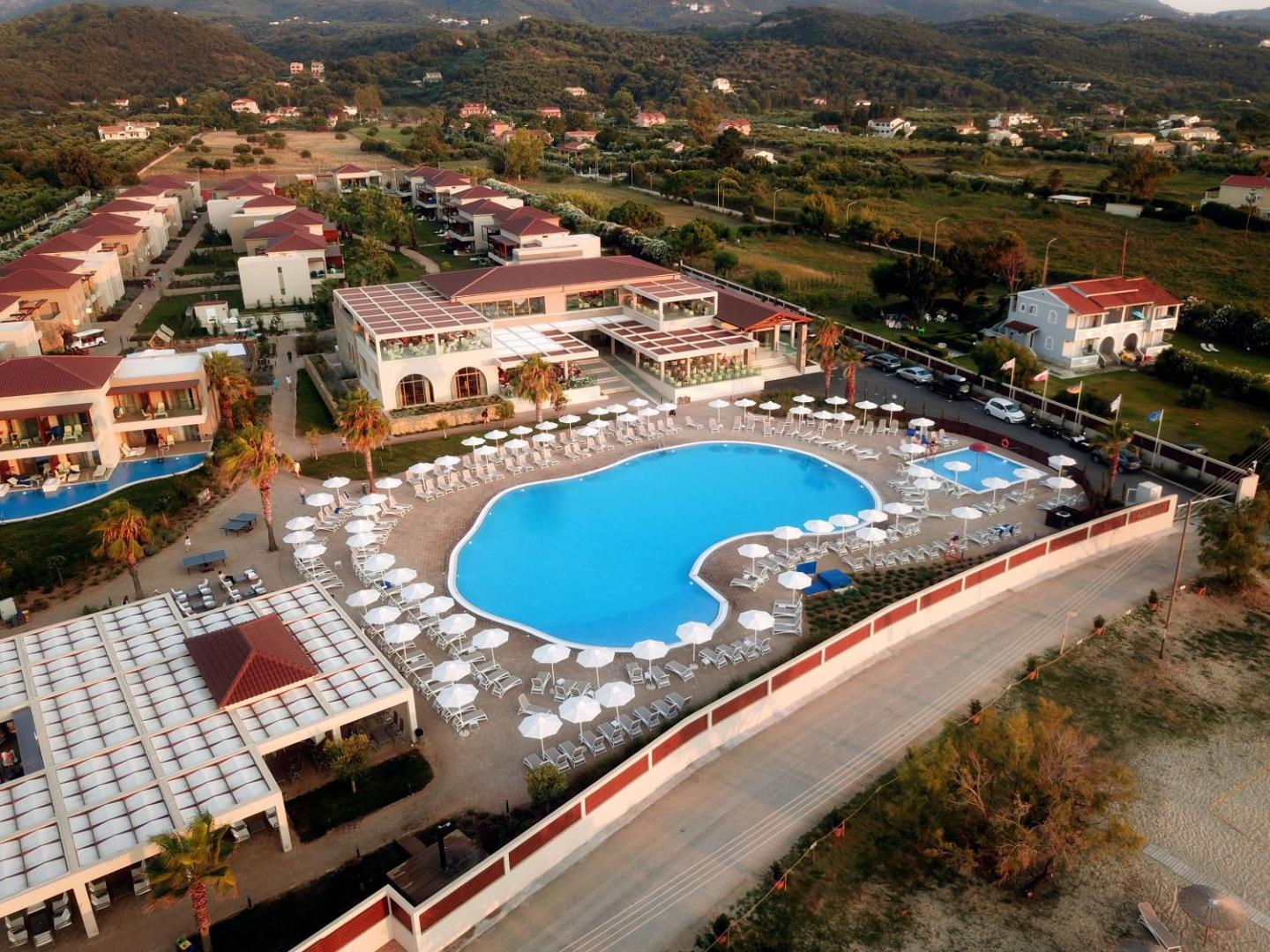 Almyros Beach Resort & Spa viesnīcas ēkas un galvenais baseins vakarā — numuri ar tiešu piekļuvi baseinam un labiekārtota teritorija