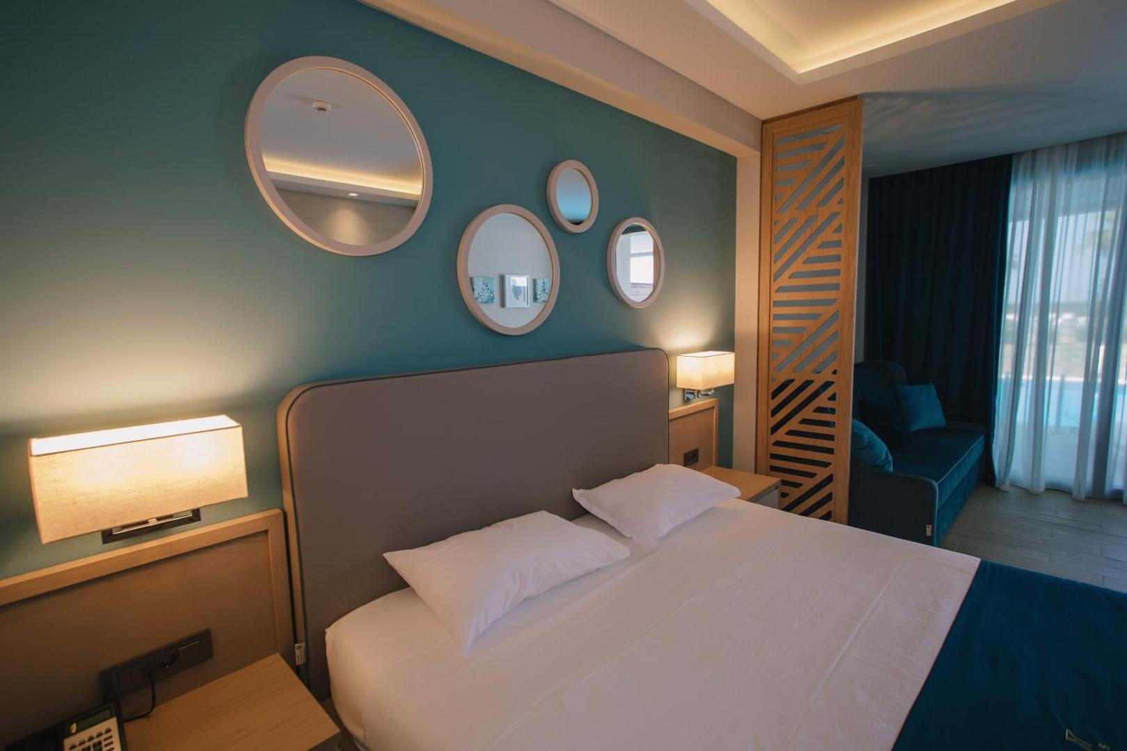 Almyros Beach Resort & Spa numura interjera detaļas ar dekoratīviem spoguļiem, koka elementiem un mīkstu apgaismojumu