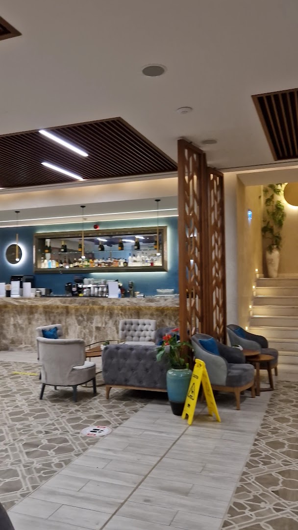 Almyros Beach Resort & Spa vestibila bārs ar mīkstiem atpūtas krēsliem, modernu interjeru un marmora leti Korfu kūrortā