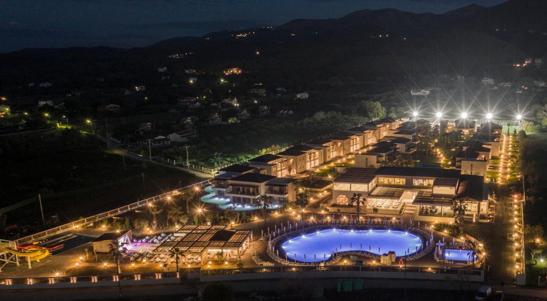 Almyros Beach Resort & Spa nakts skats ar izgaismotiem baseiniem, terasēm un numuru korpusiem Korfu piekrastē