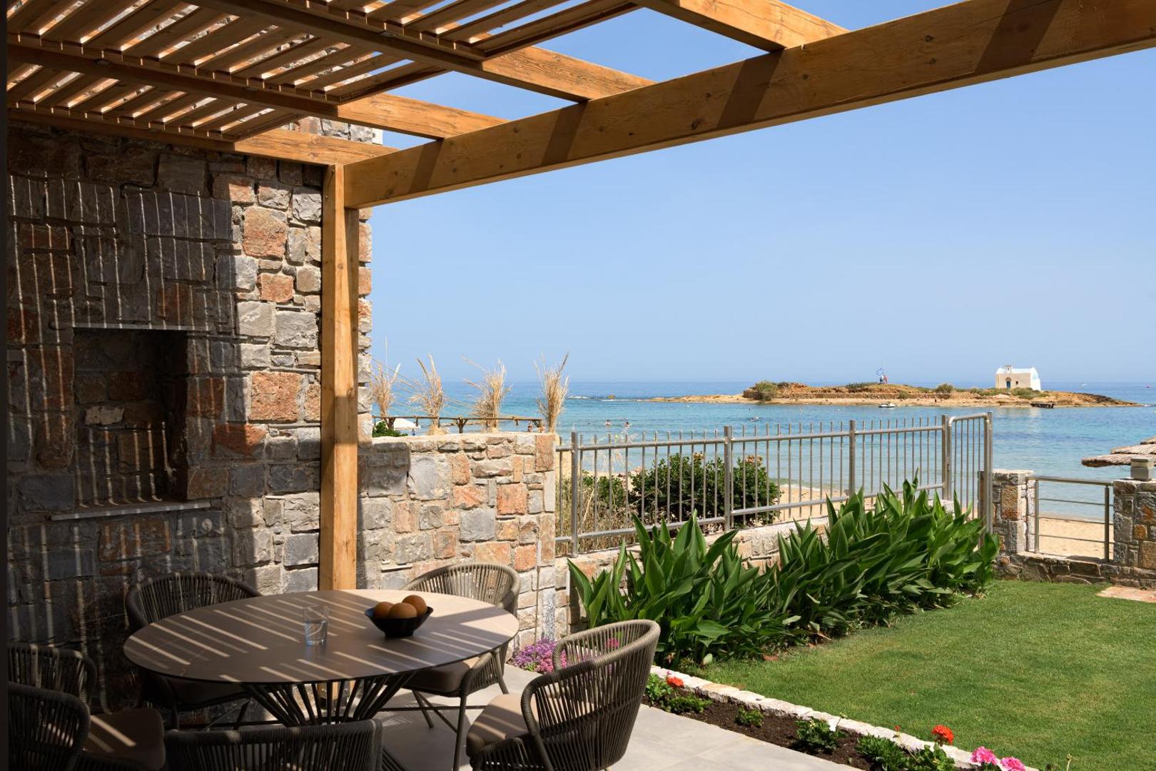 High Beach Resort pirmā stāva terase ar akmens sienu, pusdienu galdu un skatu uz jūras līci un baznīcu