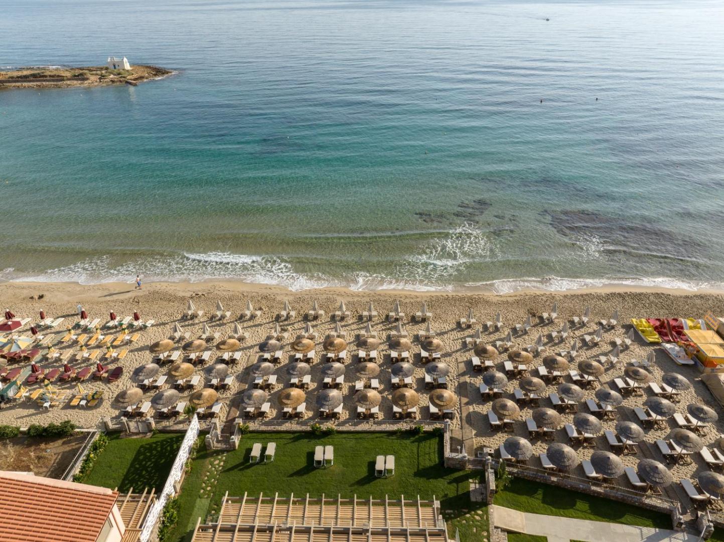 High Beach Resort plašā pludmales zona no augšas — rindu rindām saulessargi smiltīs un zāles klājs pie pašas jūras