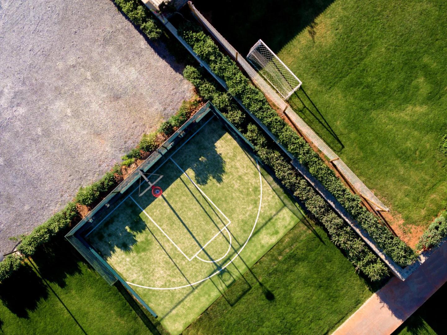 High Beach Resort sporta laukumu skats no augšas — basketbola laukums un futbola vārti uz zaļa zālāja Stalidas kūrortā