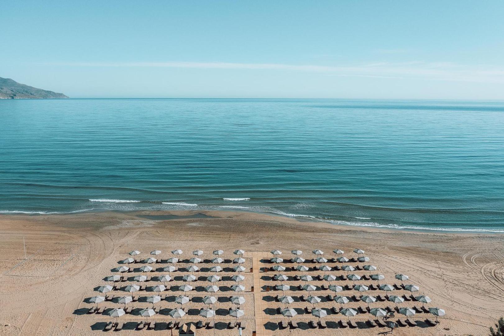 Eliros Mare Beachfront Poem Hotel panorāmas skats uz privāto pludmali ar sakārtotām saulessargu rindām un mierīgu Vidusjūru