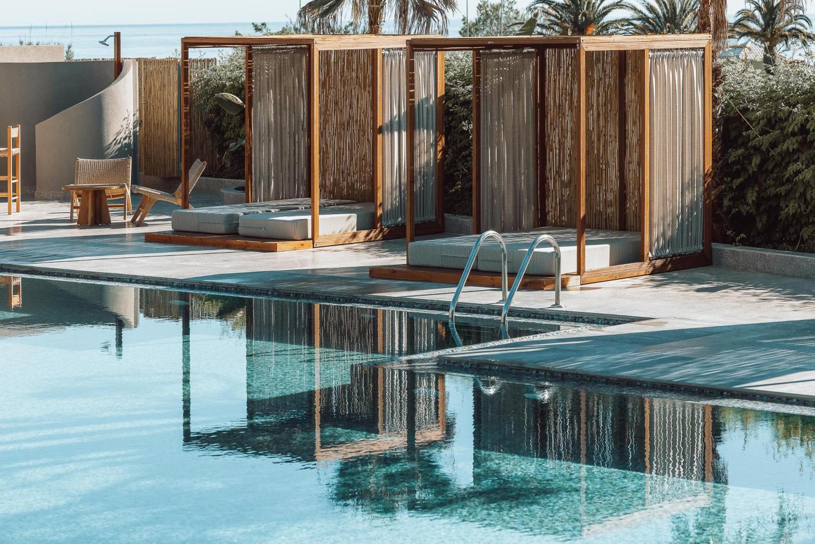 Eliros Mare Beachfront Poem Hotel privātie atpūtas bungalo pie baseina malas ar mīkstiem matračiem un aizkariem privātumam