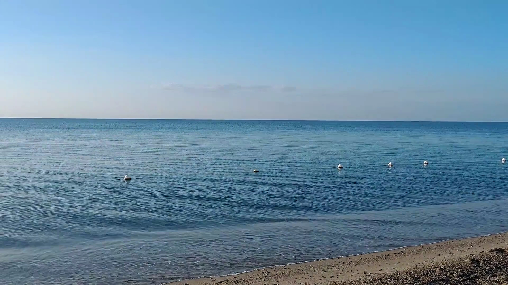 VOI Floriana Resort mierīgs jūras skats no krasta agrā rītā ar lēzenu ieeju ūdenī un skaidrām debesīm