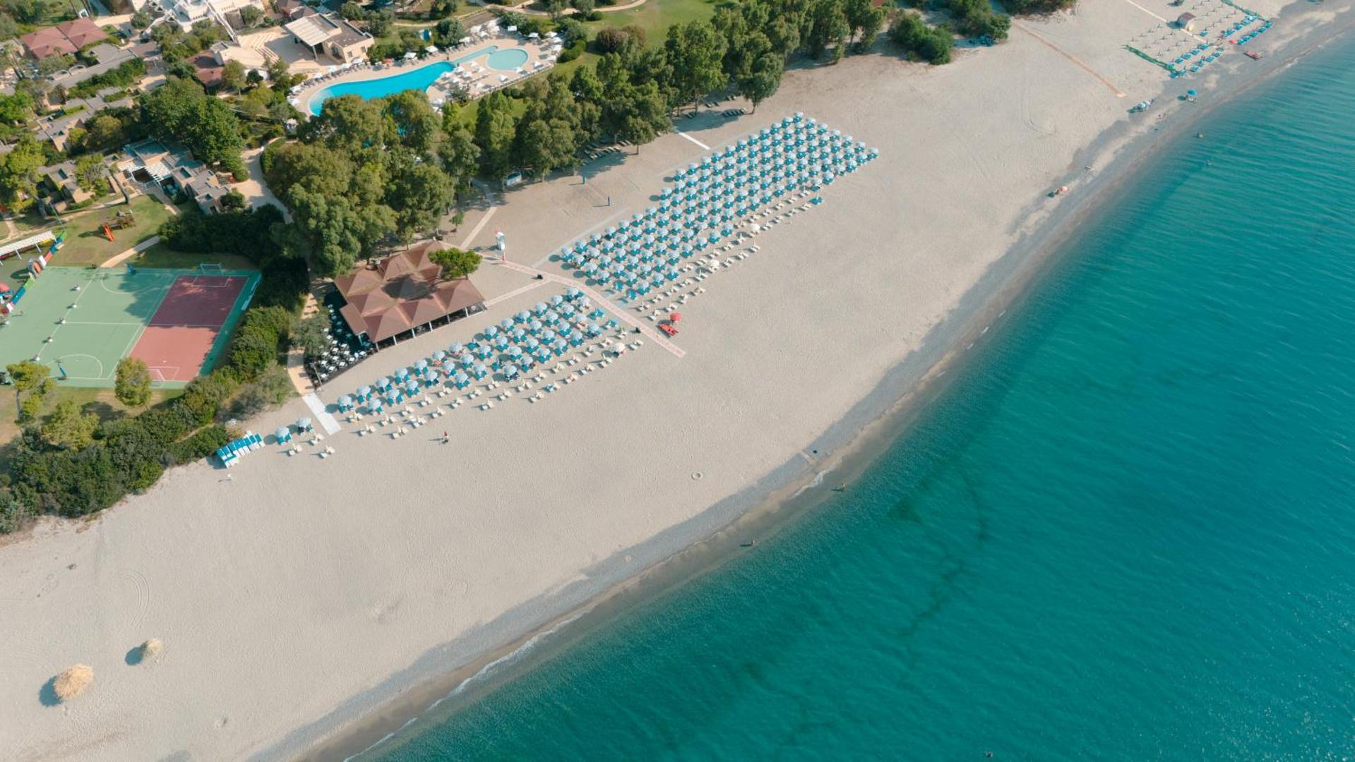 VOI Floriana Resort privātā pludmale ar saulessargiem un guļamkrēsliem pie tirkīzzila ūdens Kalabrijā, Itālijā