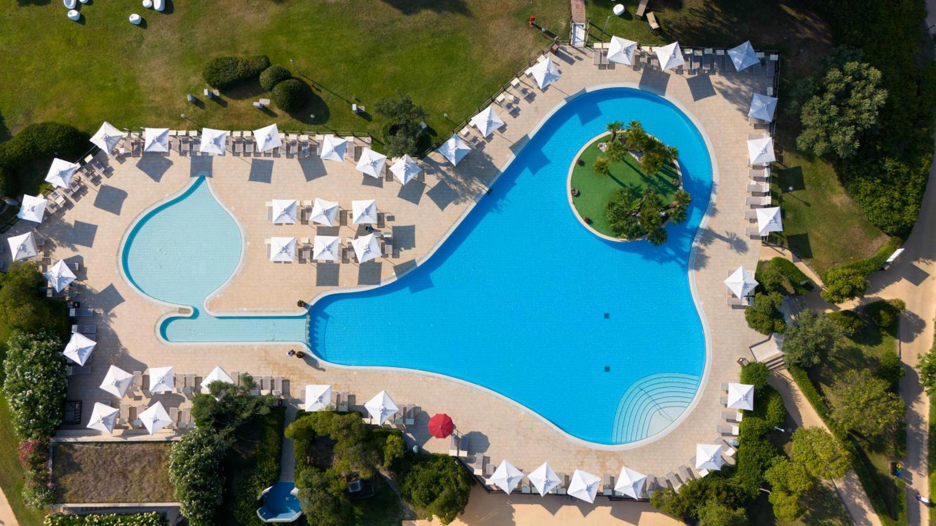 VOI Floriana Resort galvenais baseins no augšas — redzama bērnu sekcija, sauļošanās zona un apkārtējie apstādījumi