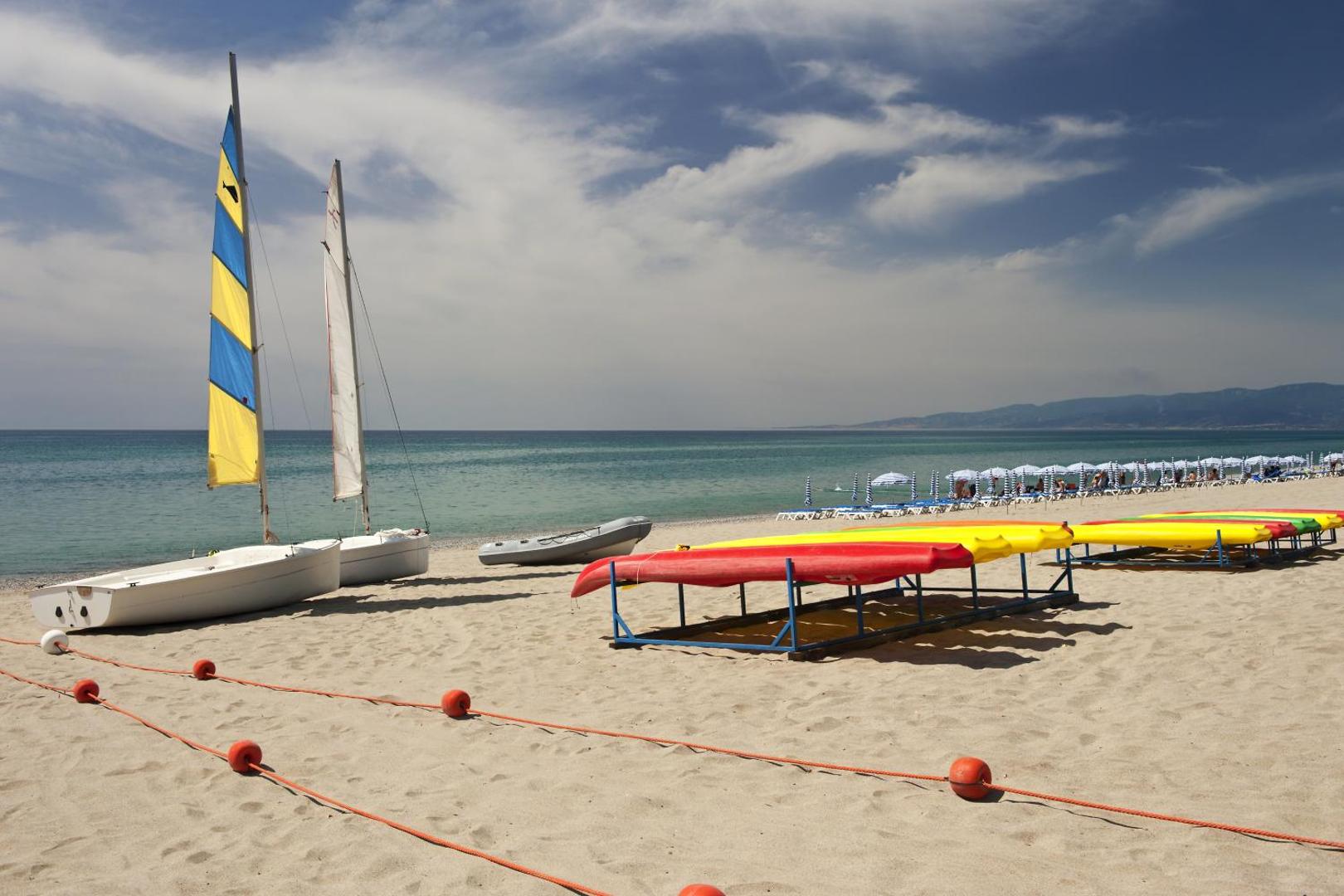 VOI Floriana Resort privātā pludmale Kalabrijā ar buru laivām, kajakiem un saulessargiem pie dzidrā Jonijas jūras krasta