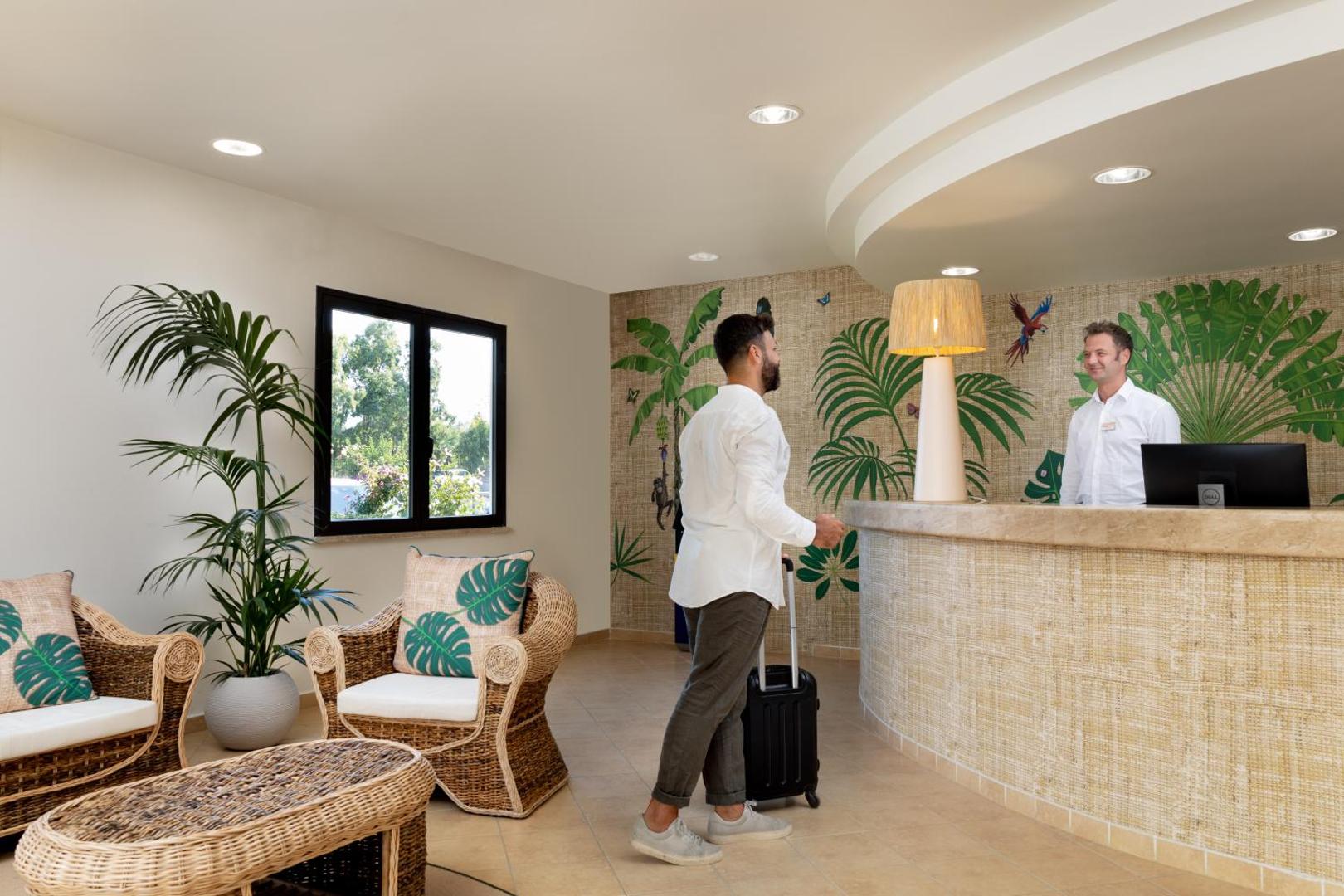 VOI Le Muse Essentia viesnīcas lobby un recepcijas zona ar tropu motīvu sienām un pītiem atpūtas krēsliem