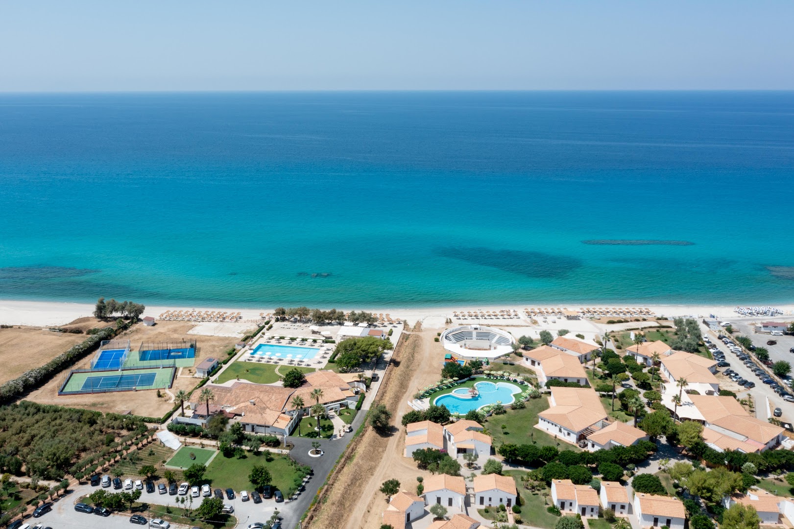 VOI Le Muse Essentia teritorijas panorāma ar tenisa kortiem, baseiniem un plašu smilšu pludmali Kalabrijas reģionā
