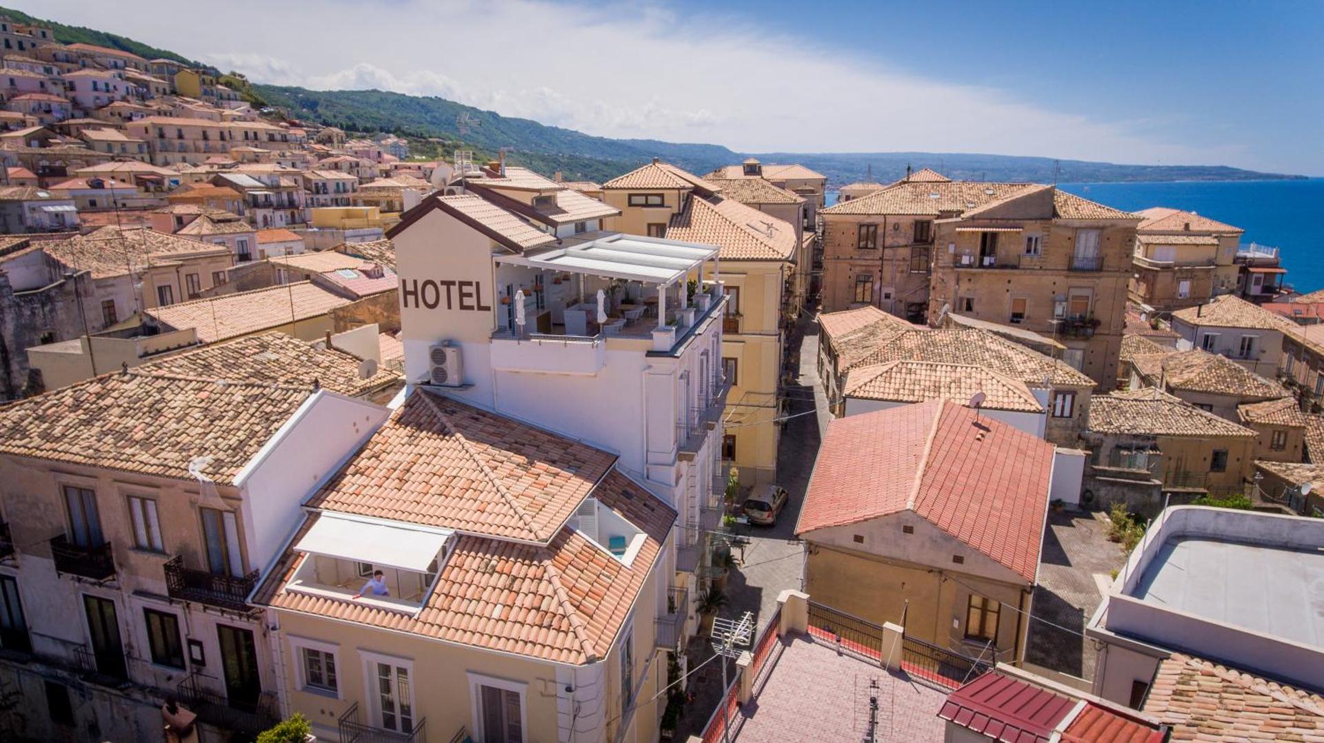 Piccolo Grand Hotel jumta terase un pilsētas panorāma ar dakstiņu jumtiem un jūru tālumā