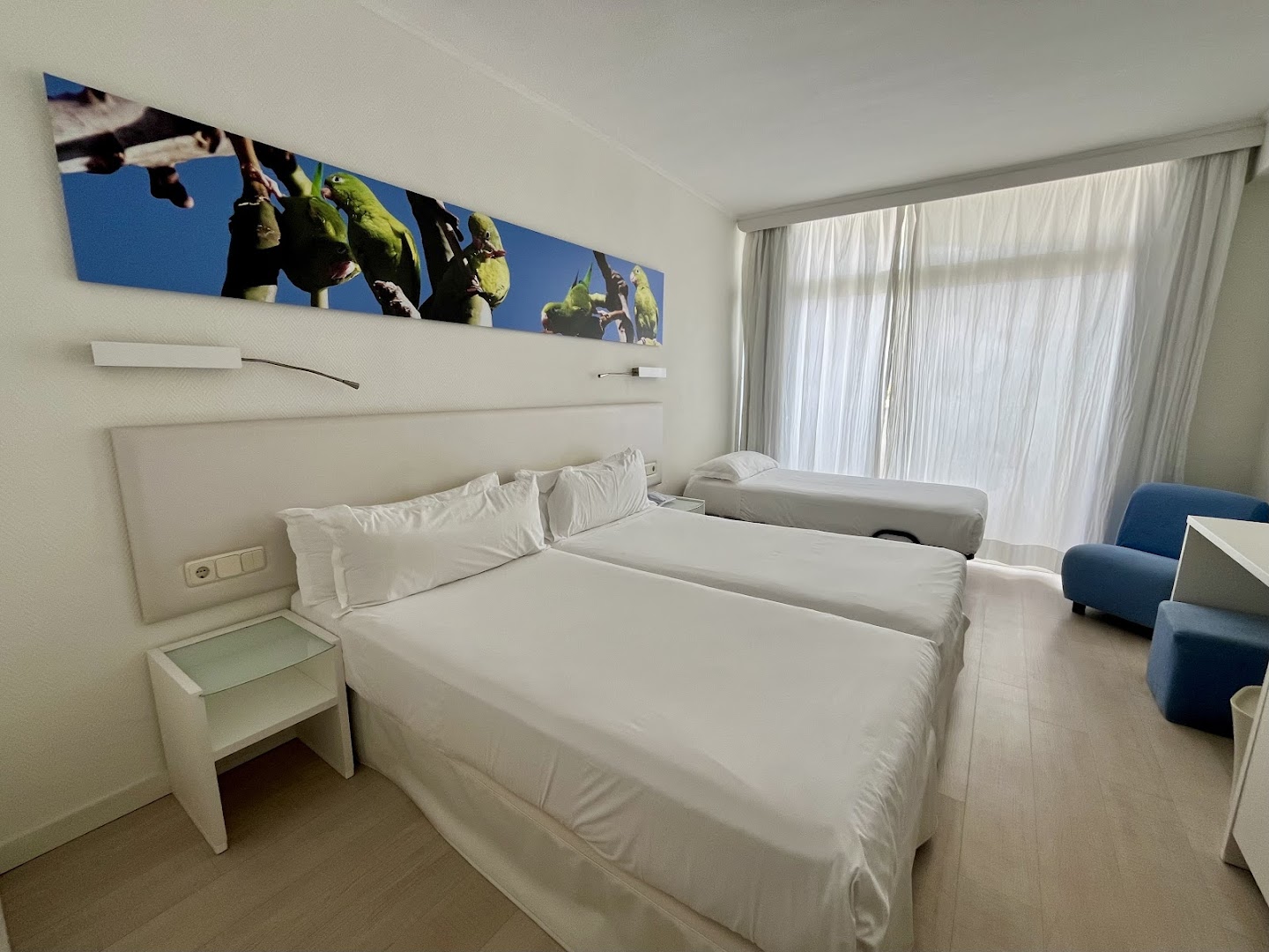 Iberostar Waves Bouganville Playa trīsvietīgs numurs ar papildu gultu un dekoratīvu sienas gleznojumu gaišā interjerā