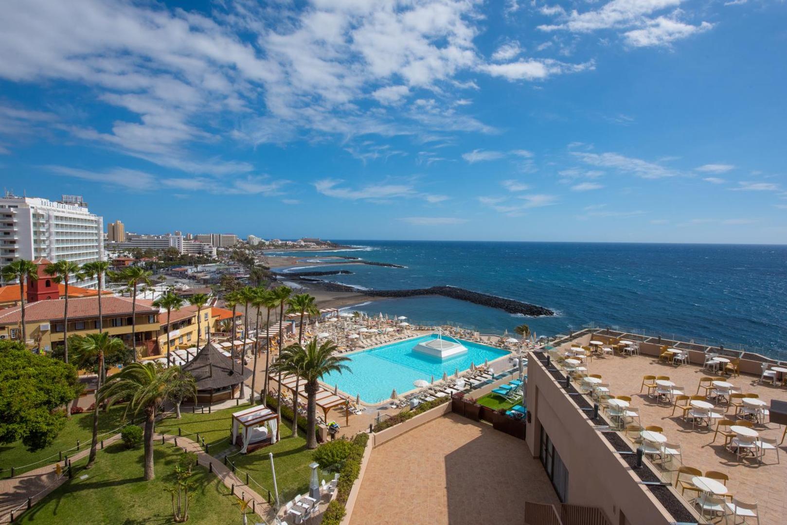 Iberostar Waves Bouganville Playa skats no augšas uz āra baseinu, terasi un okeāna piekrasti Kostadeje, Tenerifē saulainā dienā