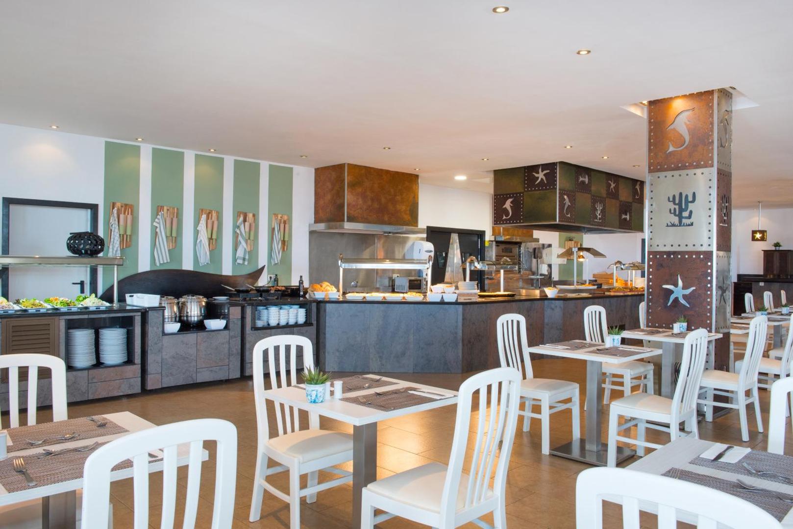 Iberostar Waves Bouganville Playa galvenais restorāns ar bufetes zonu un gaišiem koka galdiem Tenerifē — moderna brokastu un vakariņu zāle