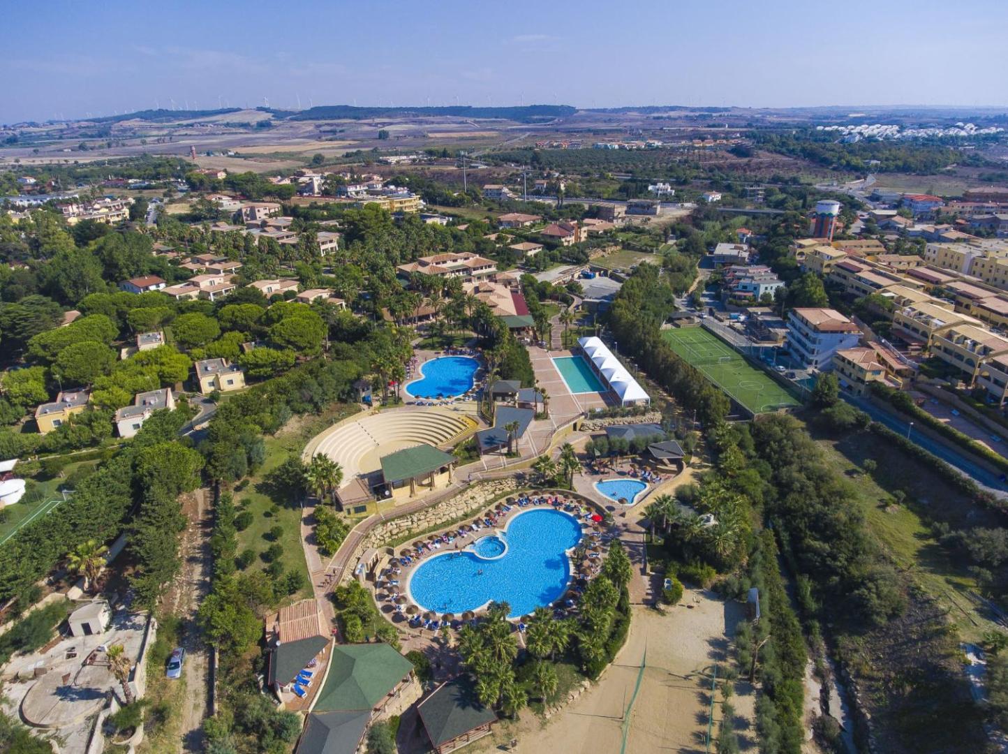 Th Le Castella Baia Degli Dei Village teritorijas skats no putna lidojuma ar vairākiem baseiniem un sporta laukumiem