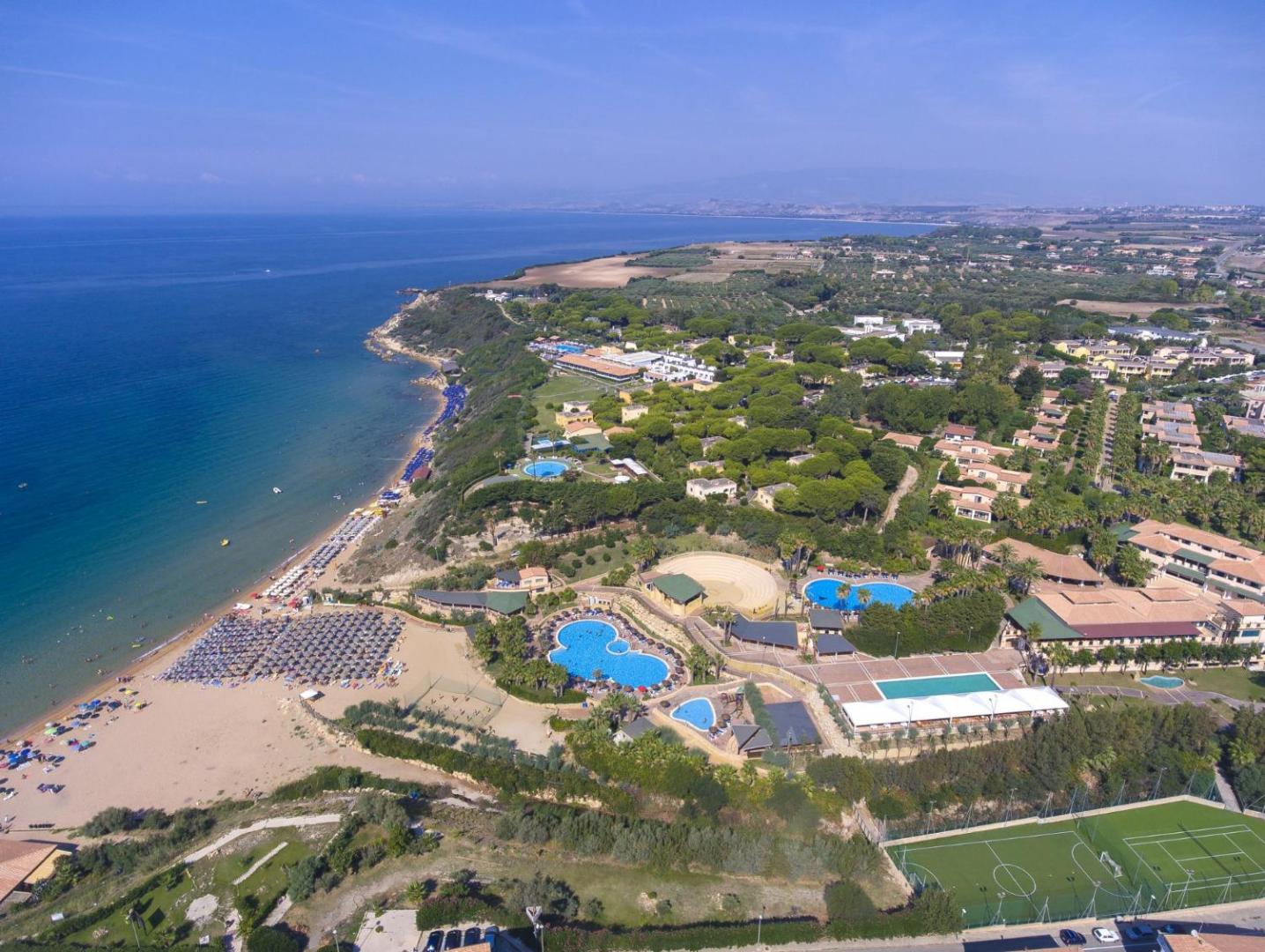 Aerofoto uz Th Le Castella Baia Degli Dei Village plašo teritoriju, privāto pludmali un apkārtējiem zaļajiem dārziem Kalabrijā