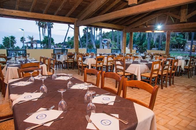 Viesnīcas Th Le Castella Baia Degli Dei Village āra terases restorāns zem koka nojumes ar skatu uz palmām