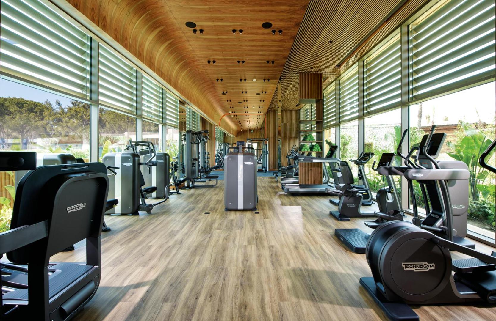 Mūsdienīgs Regnum The Crown fitness centrs ar Technogym aprīkojumu, koka apdari un plašiem panorāmas logiem