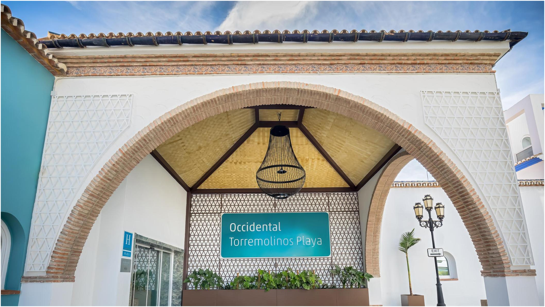Occidental Torremolinos Playa viesnīcas ieeja ar dekoratīvām arkām un zīmi Andalūzijas stilā Kostadelsoilā, Spānijā pie jūras krasta.