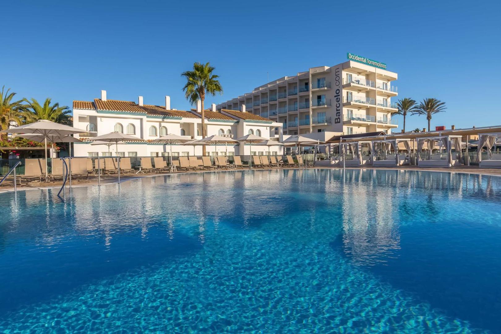 Occidental Torremolinos Playa viesnīcas ēkas skats no baseina puses Torremolinosā — gaiša arhitektūra, balkoni un labiekārtota sauļošanās zona