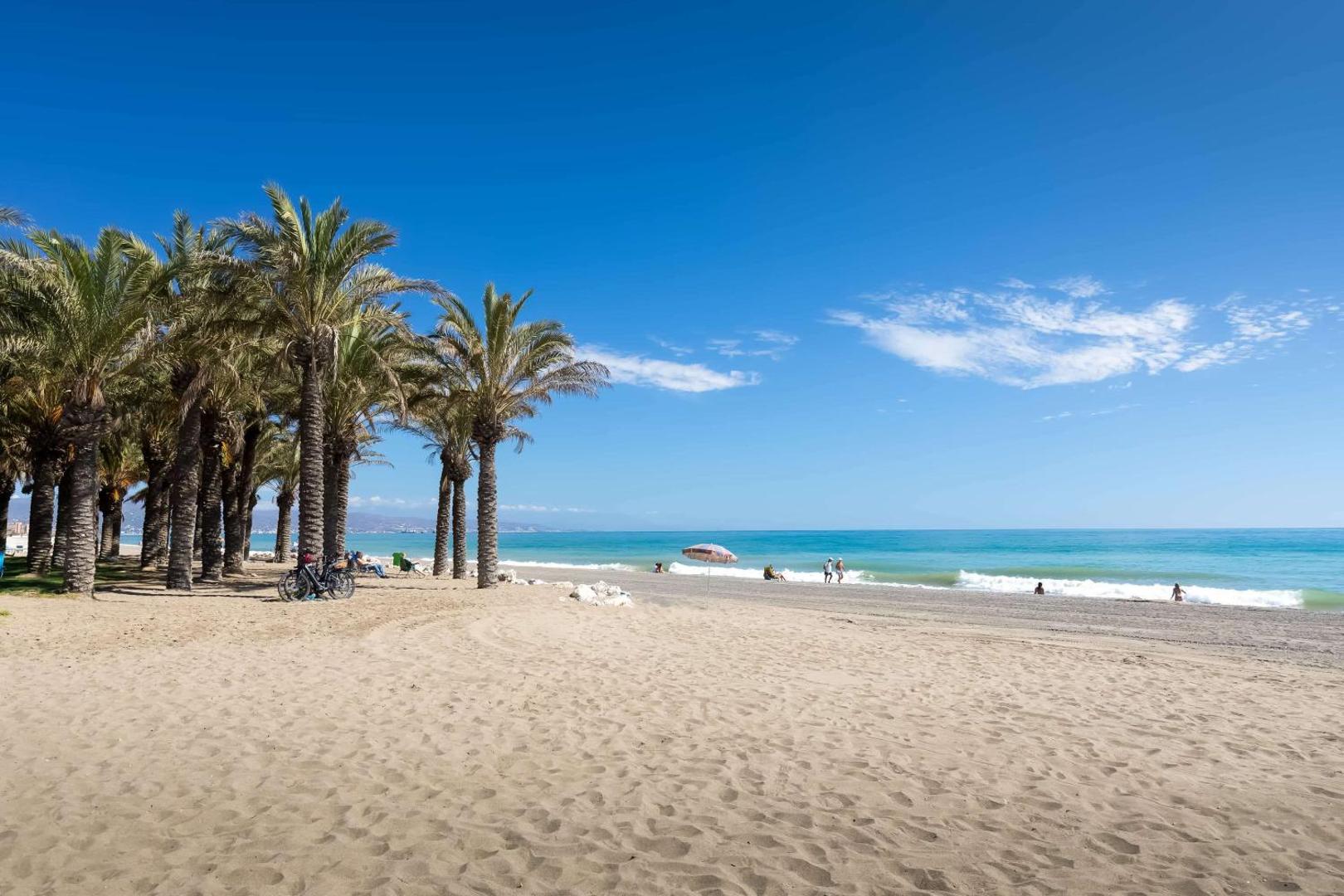 Pludmale pie Occidental Torremolinos Playa viesnīcas ar smiltīm, palmām un zilu jūru — plaša krasta līnija mierīgām pastaigām