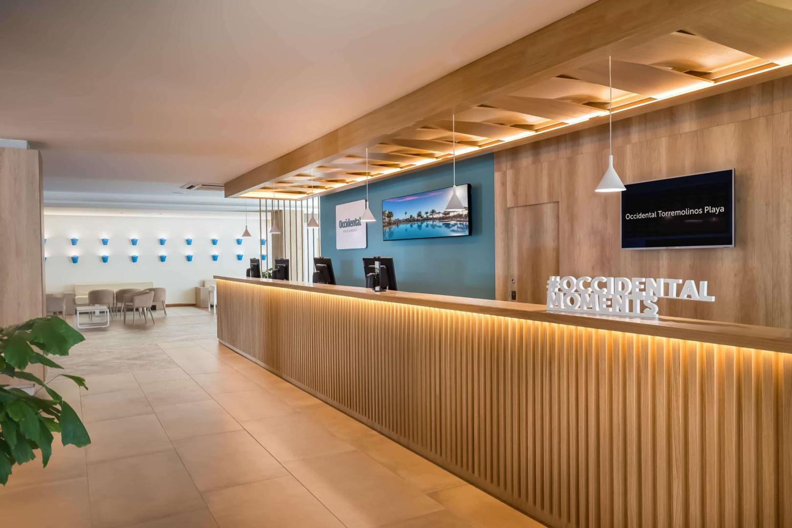 Occidental Torremolinos Playa viesnīcas recepcija ar modernu koka apdari un gaišu interjeru Torremolinosā, Spānijā — viesu uzņemšanas zona un vestibils