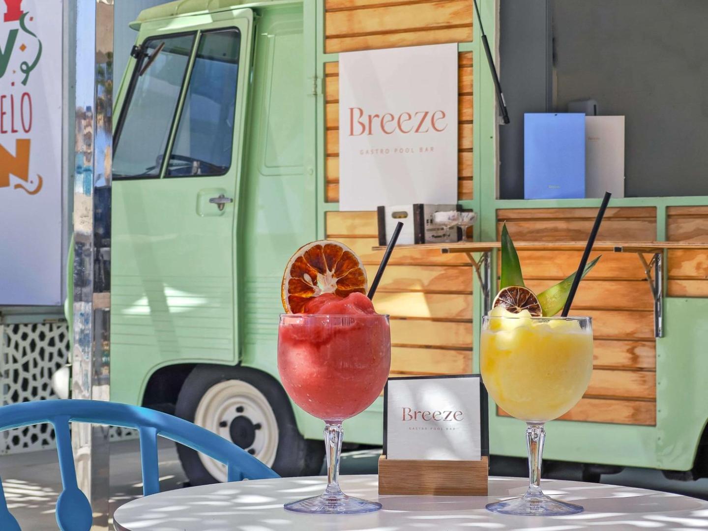 Krāsaini augļu kokteiļi uz galda Occidental Torremolinos Playa Breeze bāra fonā, kas izveidots retro stila vagoniņā