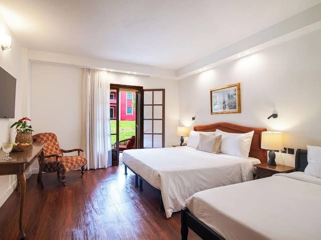 Grecotel Costa Botanica plašs ģimenes numurs ar koka grīdu, divām gultām un izeju uz terasi Korfu kūrortā.