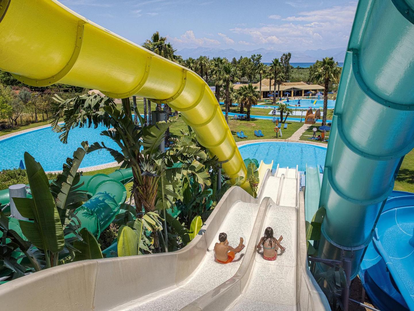 Grecotel Costa Botanica akvaparks Korfu salā ar krāsainiem ūdens slidkalniņiem un plašiem āra baseiniem palmu ieskautā teritorijā