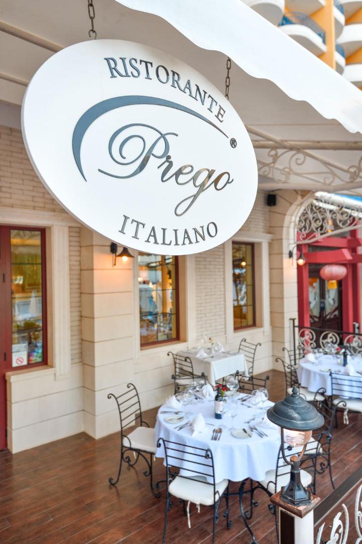Itāļu restorāns Prego viesnīcā Grifid Hotel Arabella — āra terase ar klātiem galdiem un restorāna izkārtni