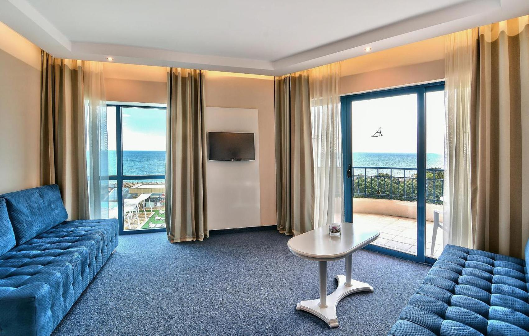 Grifid Hotel Arabella viesnīcas numura atpūtas zona ar diviem zilā toņa dīvāniem, galdiņu un plašu balkonu ar skatu uz jūru