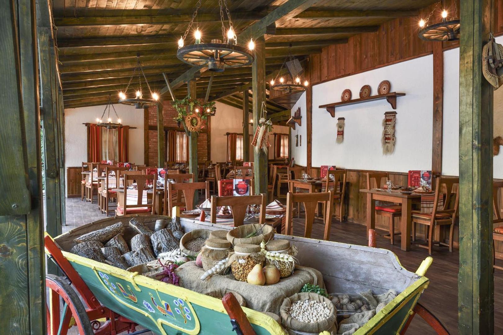 Grifid Hotel Arabella tradicionālā stila restorāns ar koka interjeru, dekoratīviem ratiem un autentiskiem bulgāru dizaina elementiem