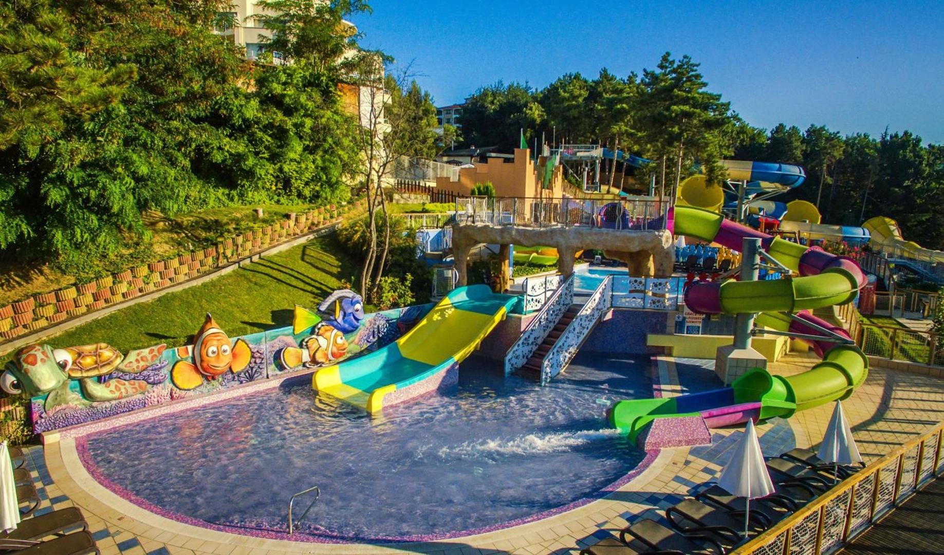 Grifid Club Hotel Bolero akvaparks ar krāsainiem slidkalniņiem un bērnu baseinu Zelta Smiltīs, Bulgārijā — atpūtas zona ar sauļošanās krēsliem